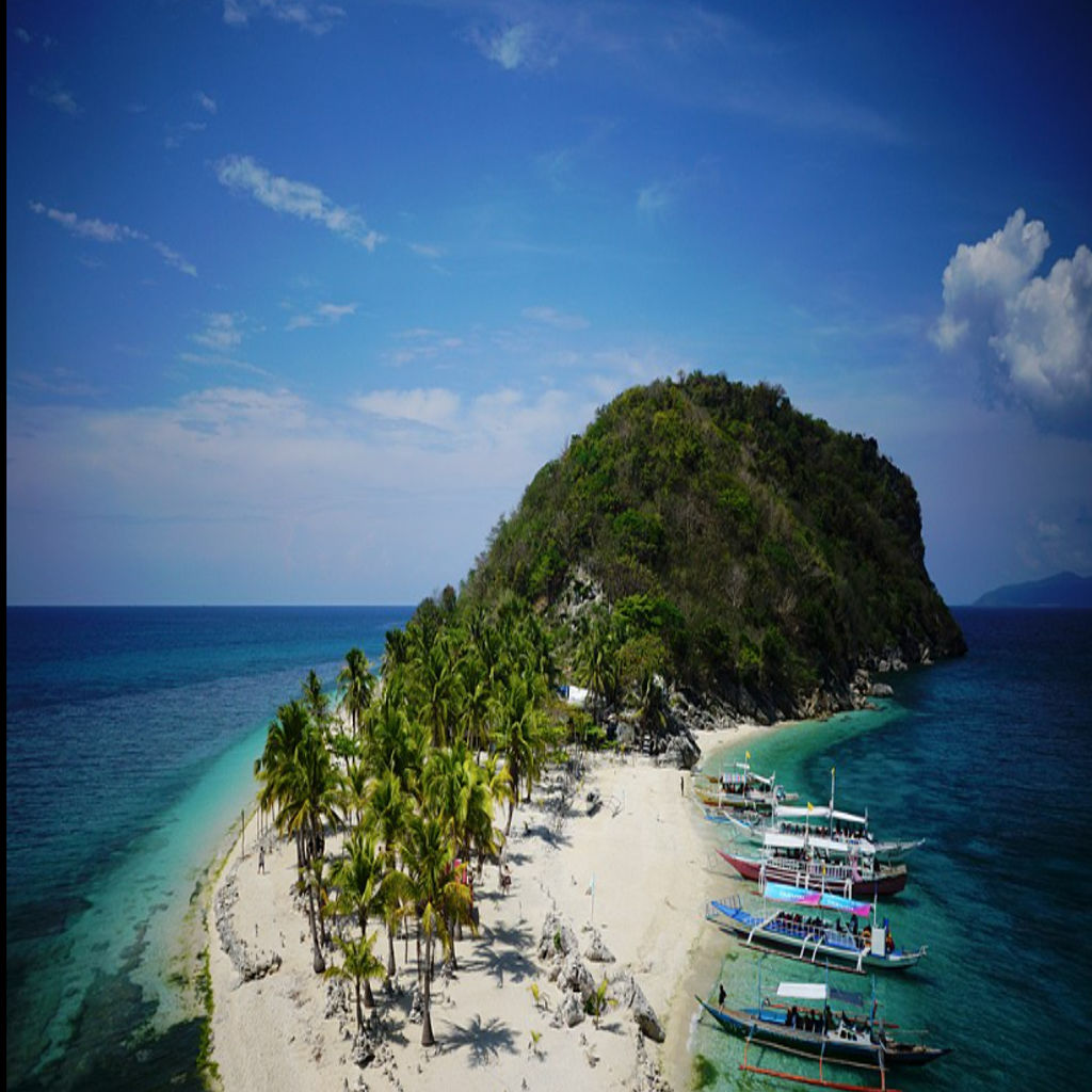 A scenic view of a tropical island landscape at Islas de Gigantes (Higantes Island). of the the top Philippines travel destination, featuring clear turquoise water, limestone cliffs, and a white sand beach with lush green trees.