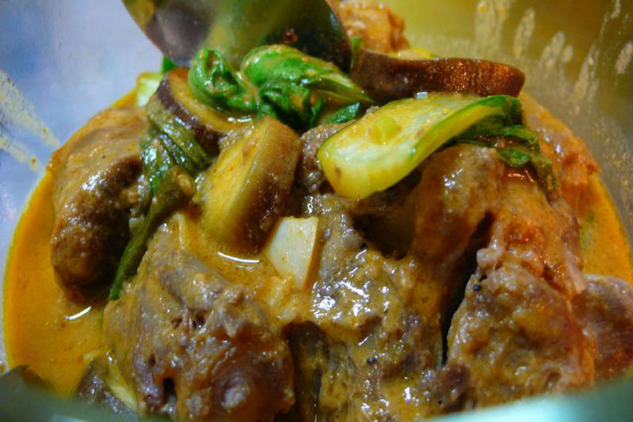 A bowl of Kare-Kare, a traditional oxtail stew in a thick, savory peanut sauce with vegetables, an iconic Philippine exotic foods dish.