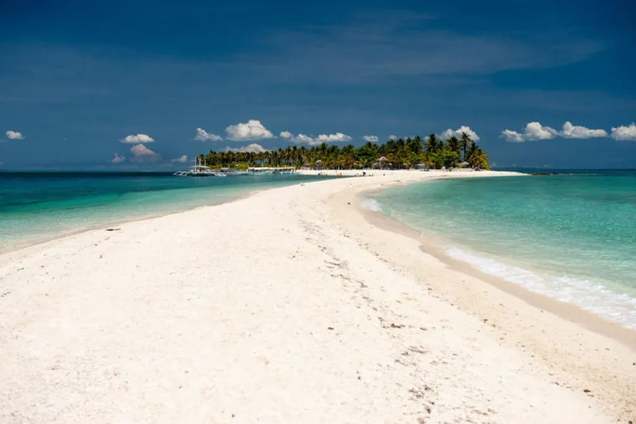 Pristine Philippine white sandbars with lush coconut trees at its wider end, stretching into clear blue waters.