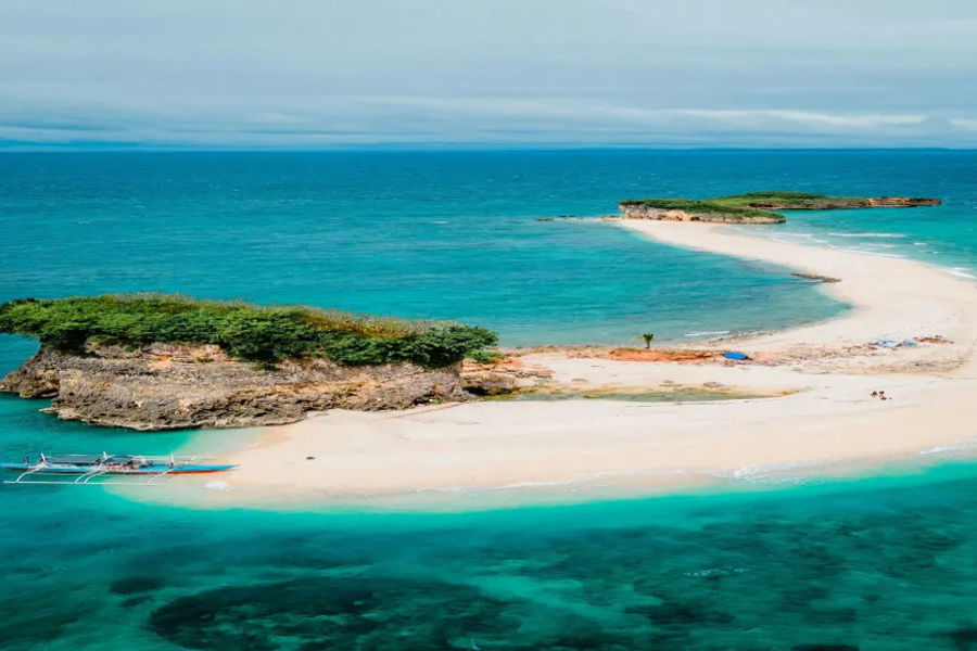 A distinctive letter S Philippine white sandbars extend into the clear blue ocean,