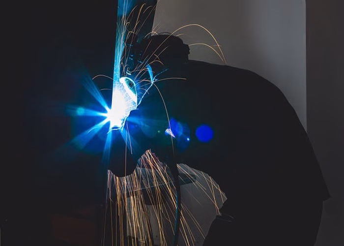 A close-up shot of a skilled Filipino welder wearing a welding helmet and protective gear, focused on their work with a bright welding arc. Welders is needed to fill POEA Jobs in Poland.